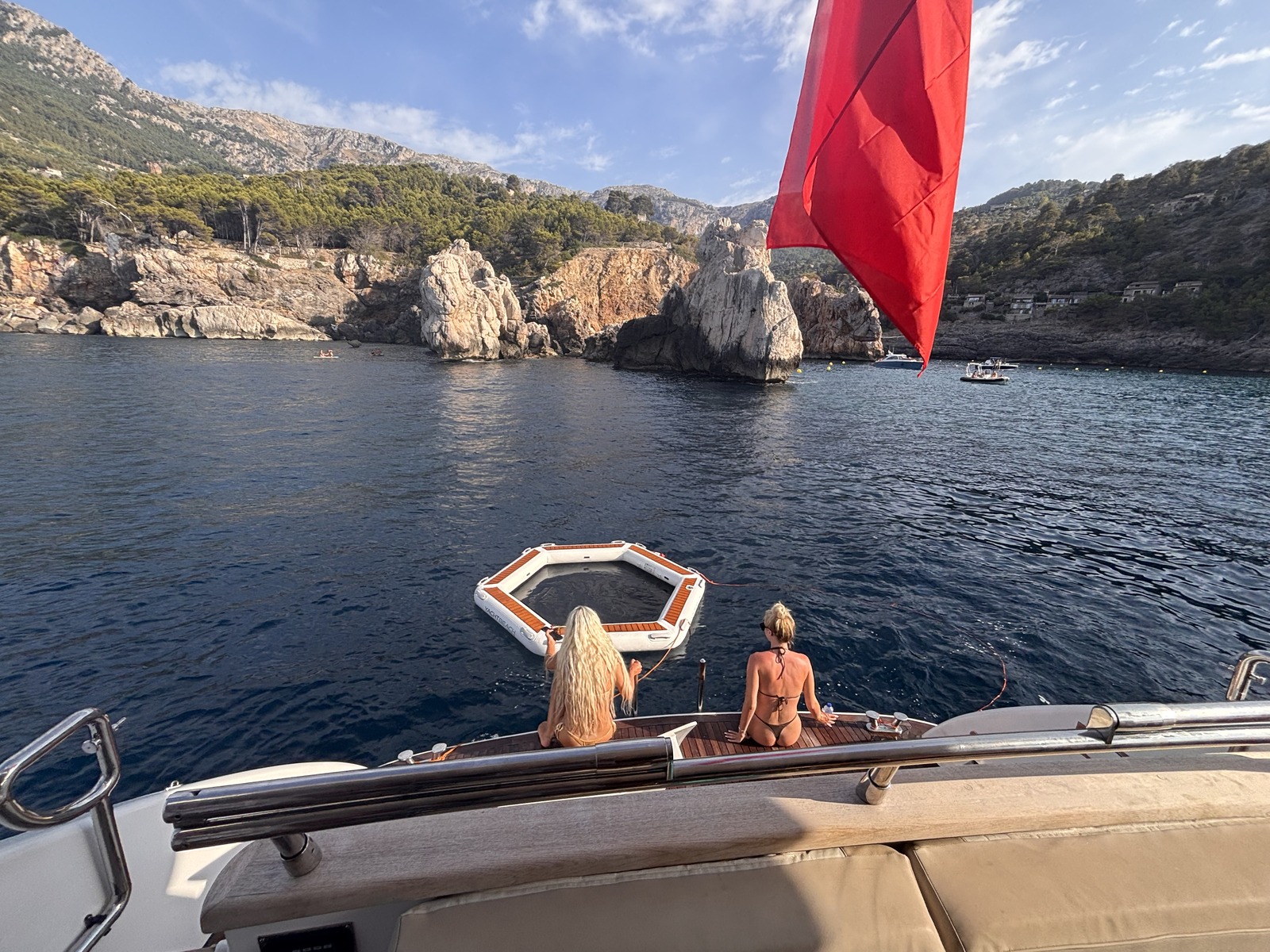 Guests on the swim platform with a floating pad in a rocky Mallorca cala