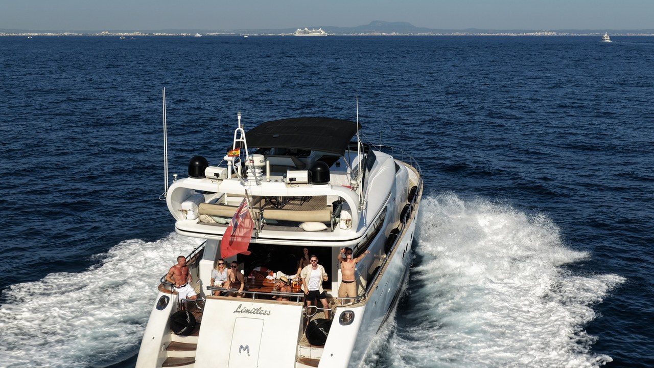 Aerial stern view of the Limitless yacht underway with guests on the aft deck