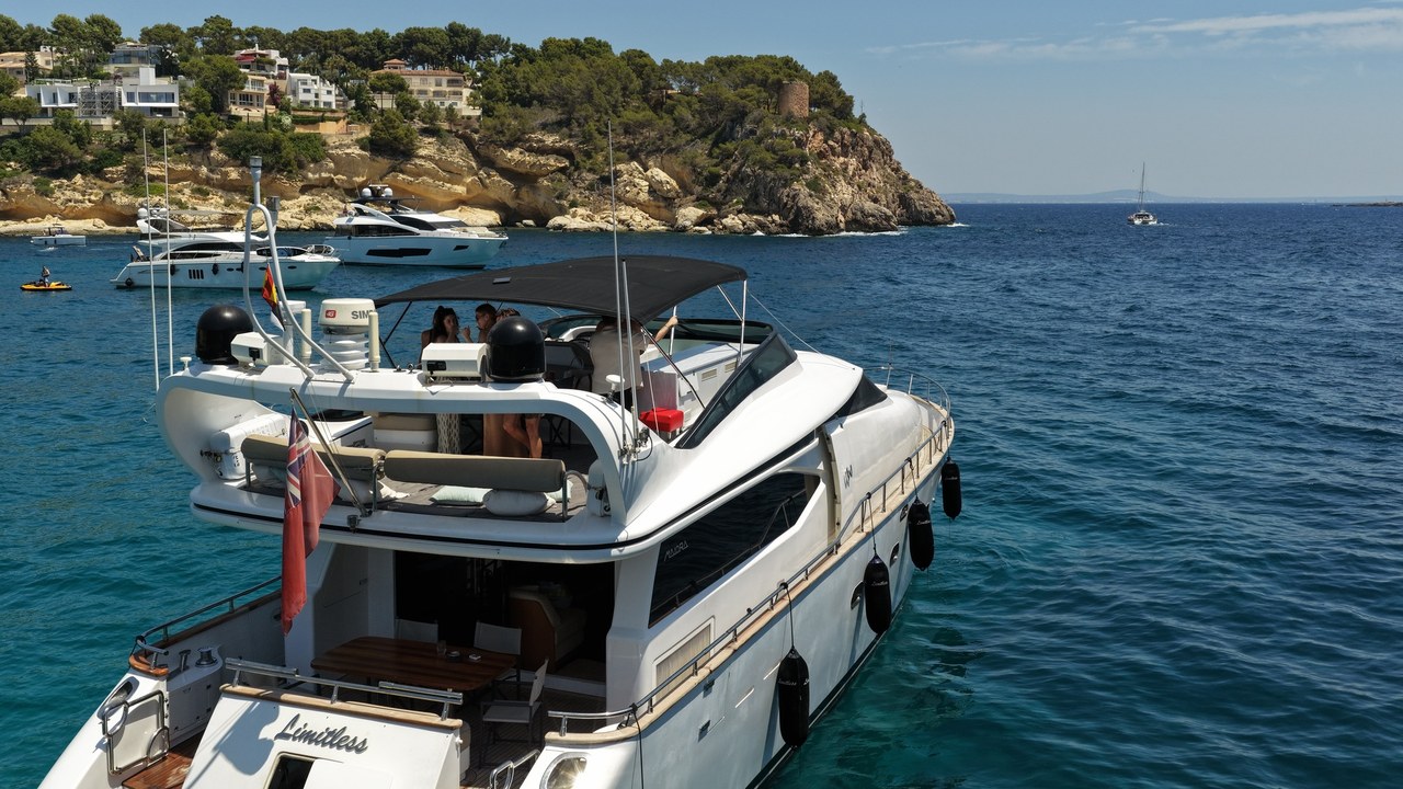 Limitless at anchor with guests on the swim platform in a Mallorca cove